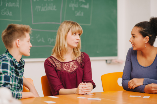 Text-Bild Tandemunterricht Schüler und Lehrerin am Tisch